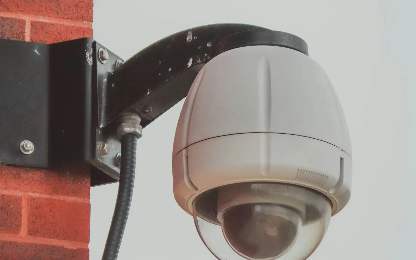 Cámara domo de videovigilancia en un muro de ladrillo